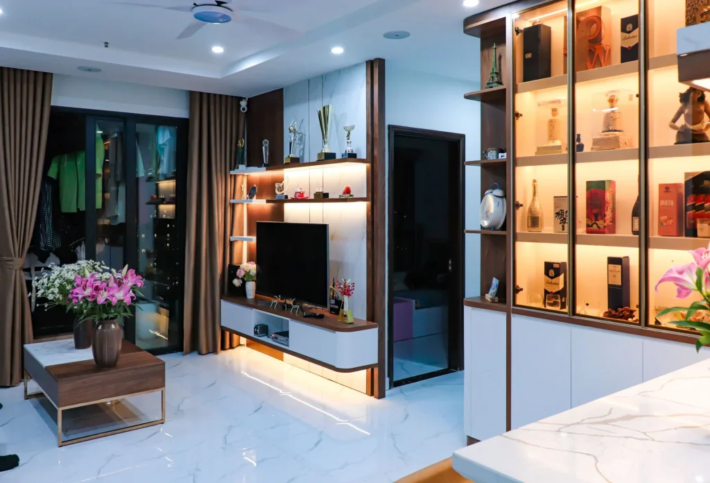 Sleek modern living room with illuminated shelves, TV unit, and floral decor.
